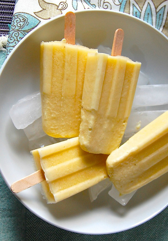 Delicious yellow popsicles on ice in white bowl