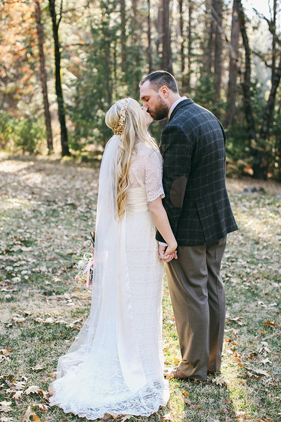 Bride and groom sharing a kiss during a forest wedding ceremony