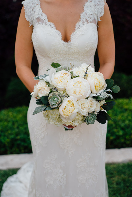 Bride in a lace dress holding a beautiful white floral bouquet