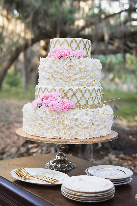Elegant white wedding cake with gold accents and pink roses