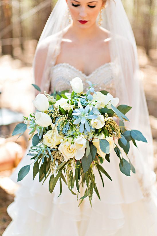 Elegant bride holding a bouquet of white flowers and greenery