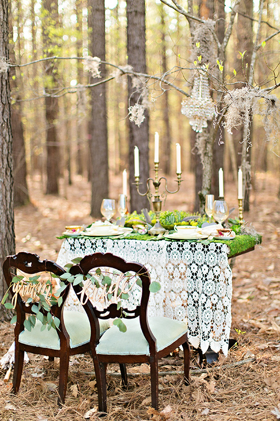 Romantic forest wedding table setting with chairs and chandelier