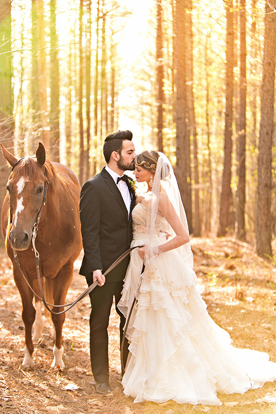 Romantic wedding couple with horse in a sunlit forest setting
