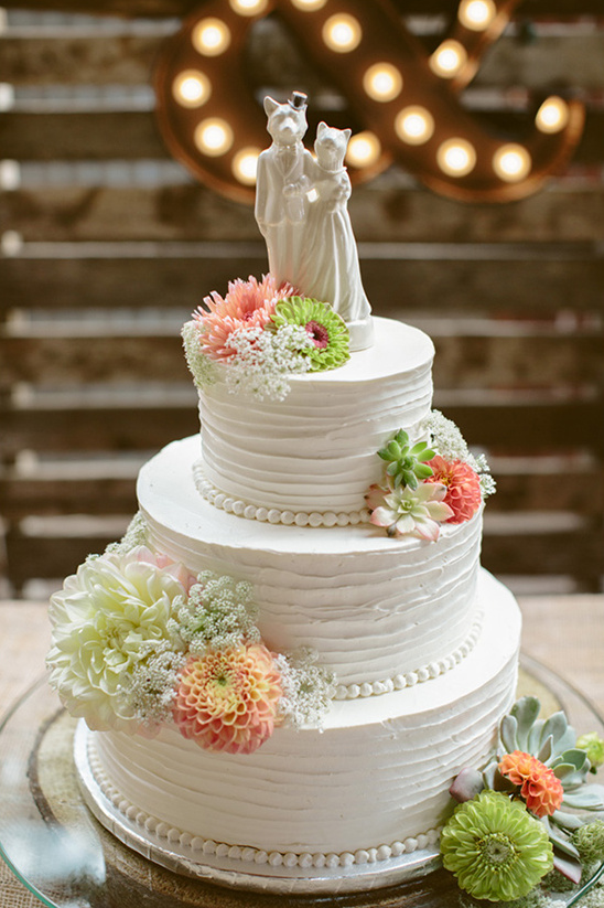 Wedding cake with floral accents and adorable animal toppers