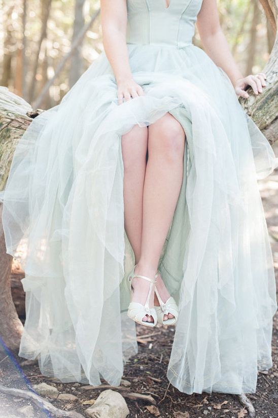Woman sits on log in flowing mint green tulle gown