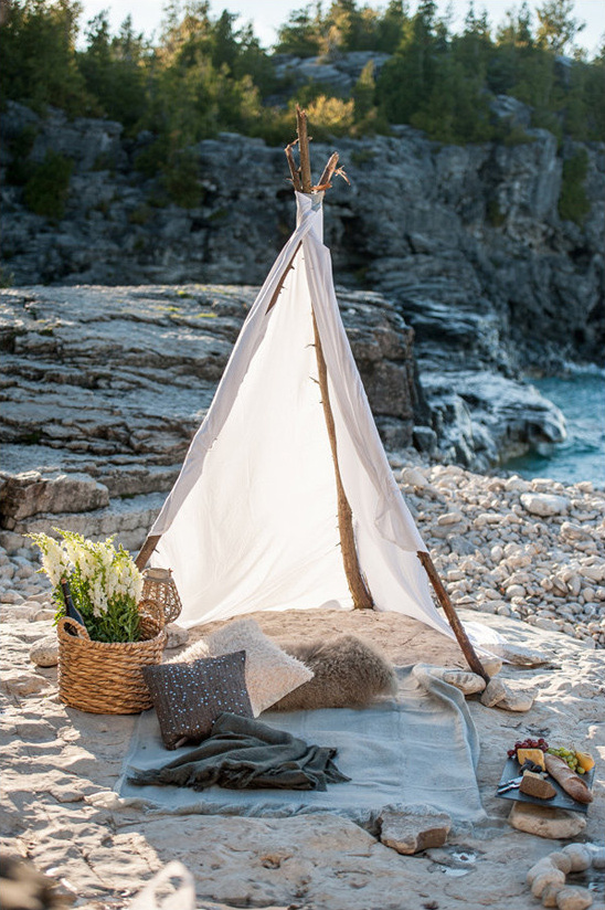 Bohemian teepee picnic setup on a scenic rocky shore