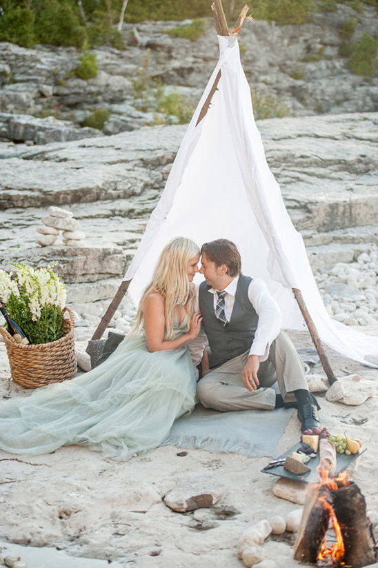 Boho couple enjoys romantic beach picnic inside teepee