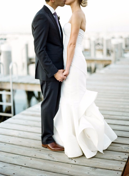 Romantic wedding kiss on a wooden dock by the water