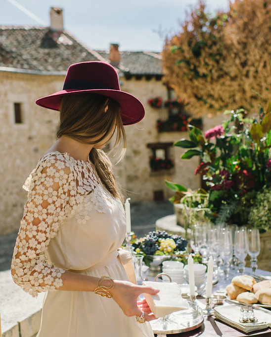 Woman in maroon hat serving food at elegant outdoor event