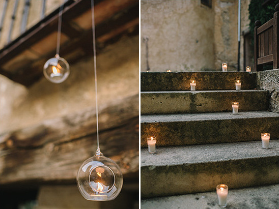 Warm candles illuminate a rustic stone staircase and hanging orbs