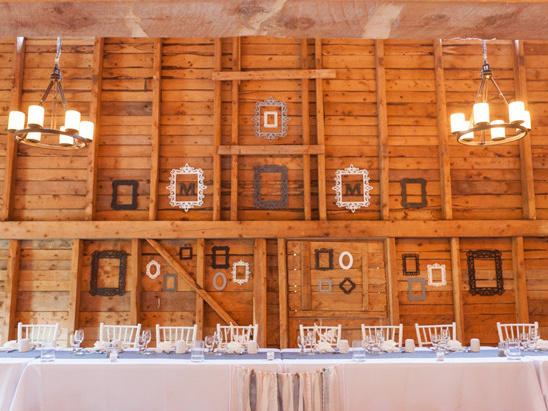 Rustic barn wedding reception table beneath wood wall decor