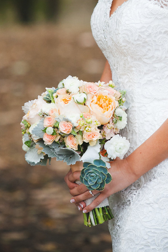 Bride holding a beautiful wedding bouquet with roses and succulent