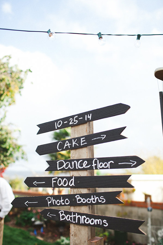 Wedding direction sign with cake, food, and dance floor details