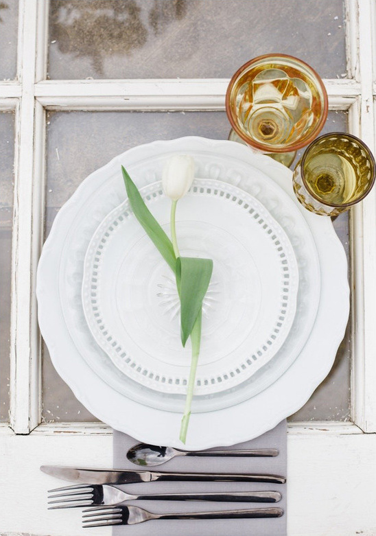 Elegant table setting with white tulip and plates, silverware