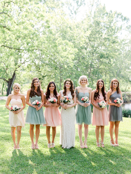 Bridesmaids in pastel dresses hold bouquets at outdoor wedding