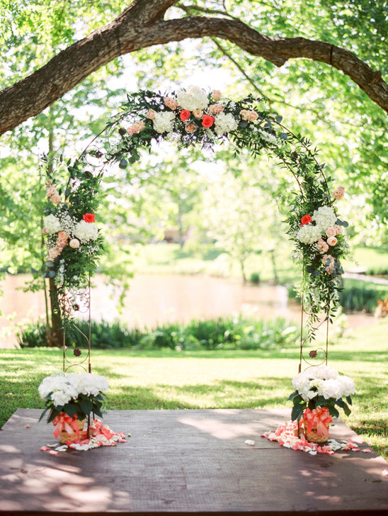 Floral wedding archway on a wooden platform outdoors