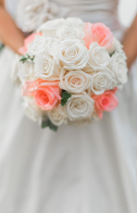 Bride holds wedding bouquet of white and peach roses