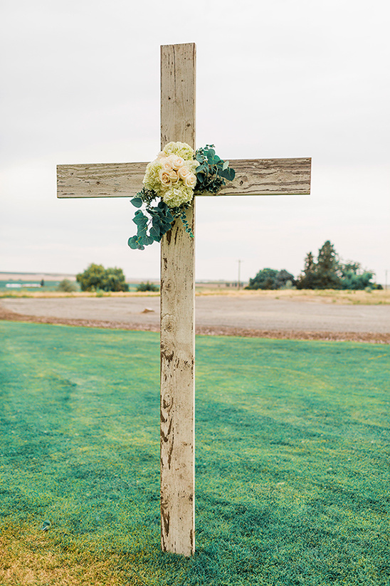 Rustic wooden cross adorned with floral arrangement outdoor