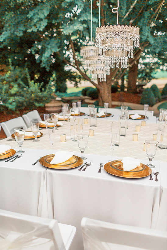 Outdoor wedding table setting with chandeliers hanging