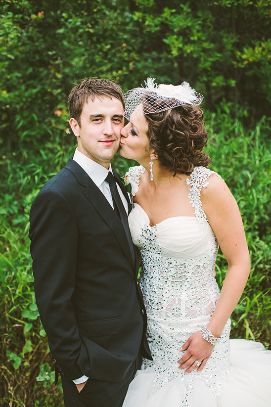Bride kissing groom on cheek at their outdoor wedding