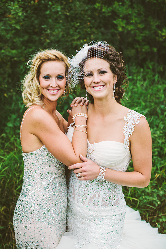 Bride and bridesmaid in elegant sparkling gowns smiling