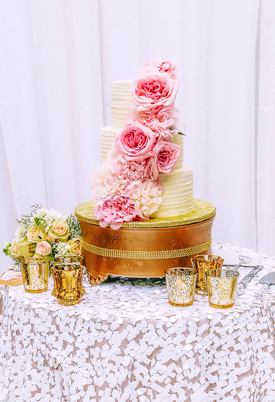Elegant three-tier wedding cake adorned with pink roses