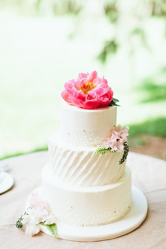 white wedding cake with peony topper @weddingchicks