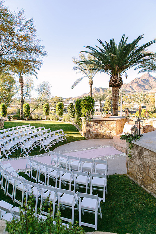 Outdoor wedding venue setup with white chairs and aisle