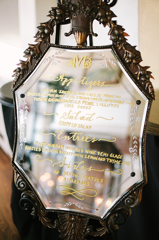 Elegant wedding menu displayed on ornate mirror easel