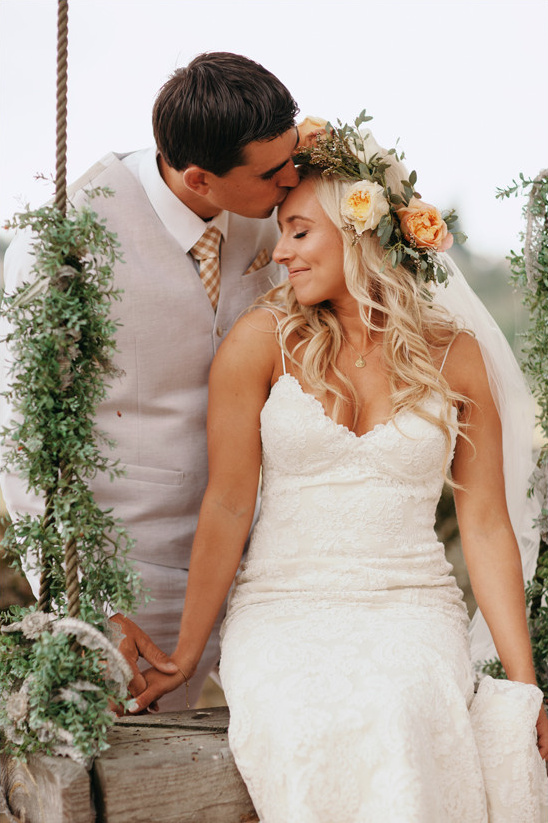 Bride and groom embrace on a swing at their wedding