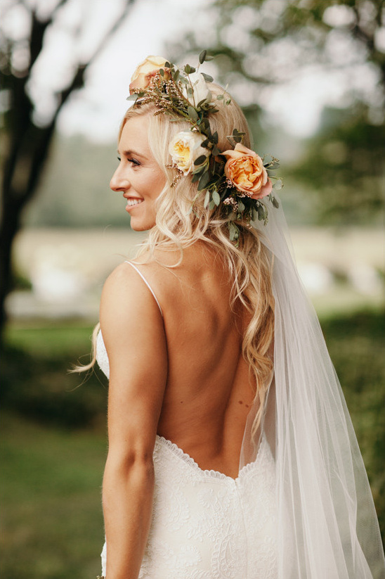 Blonde bride with floral crown and veil smiling outdoors