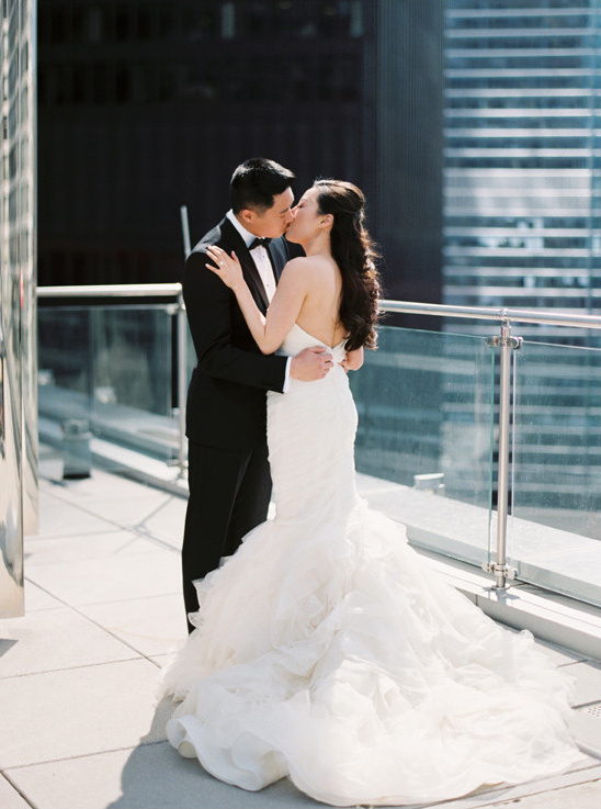 Bride and groom kissing on a city rooftop wedding day