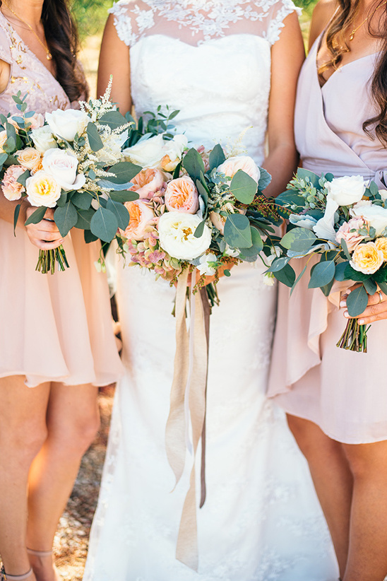 Bride and bridesmaids holding floral bouquets outdoor