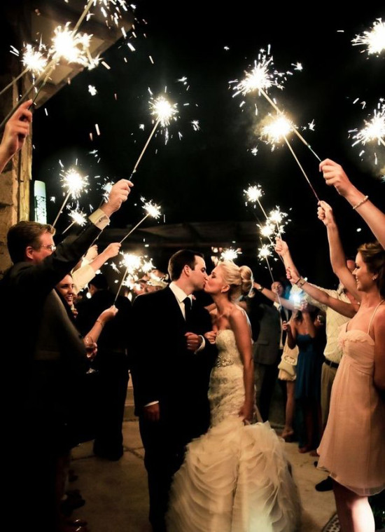 Bride and groom kissing under sparklers at their wedding