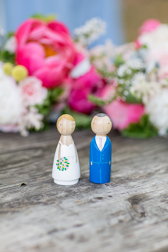 Wooden bride and groom figurines with flower bouquet