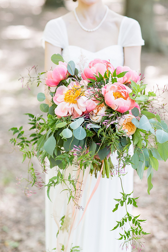 Bride holds pink peony and greenery wedding bouquet