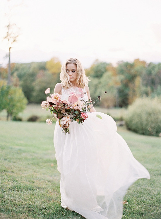 Bride in flowing gown holds bouquet outdoors