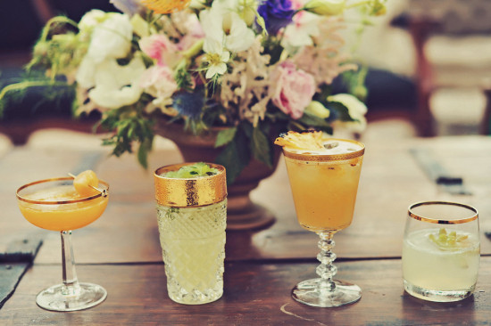 Four elegant cocktails with a beautiful floral arrangement as background