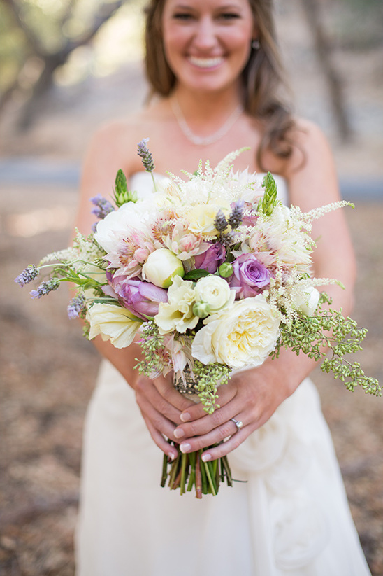 Smiling bride with white and purple wedding bouquet