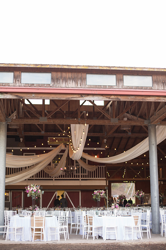 Rustic barn wedding reception venue decorated with fabric and lights