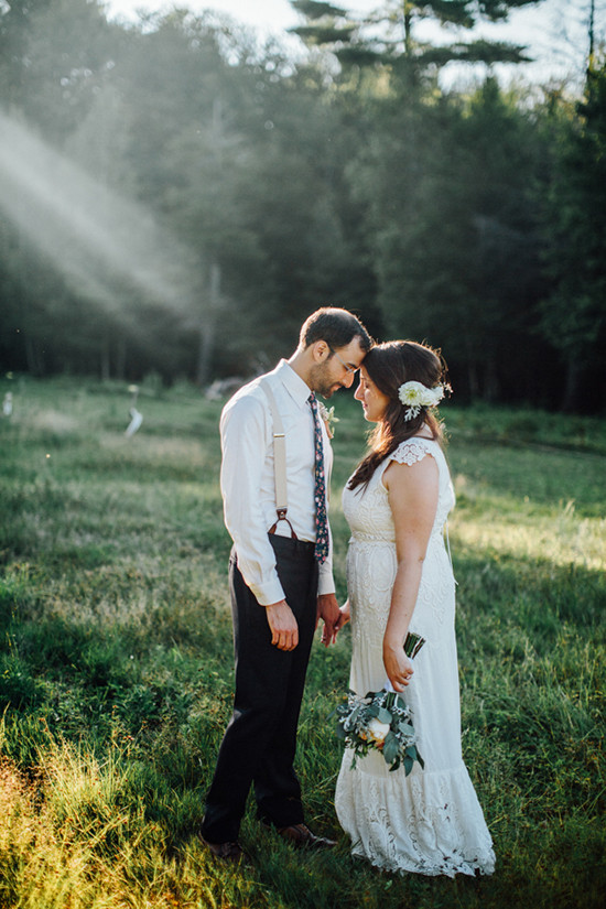 Romantic wedding couple embracing in a sunlit field