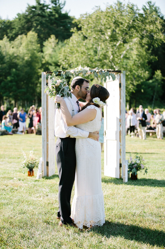 Bride and groom kiss at rustic outdoor wedding ceremony