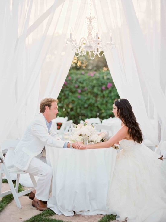Newlyweds holding hands at an elegant outdoor wedding