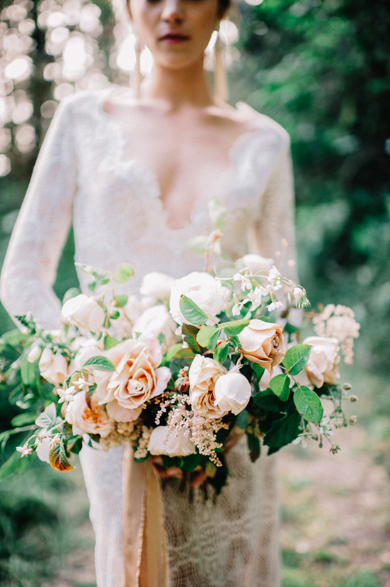 Bride in lace gown holding pastel rose bouquet