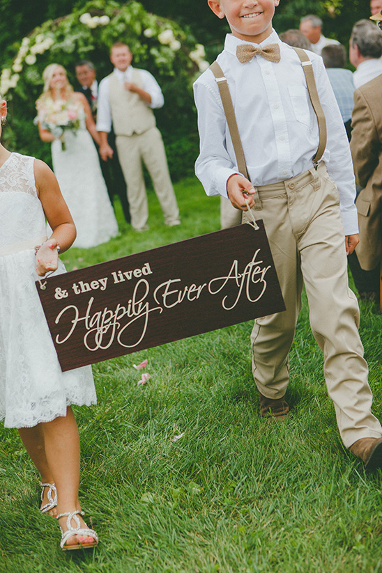 Happily Ever After sign held by children at outdoor wedding