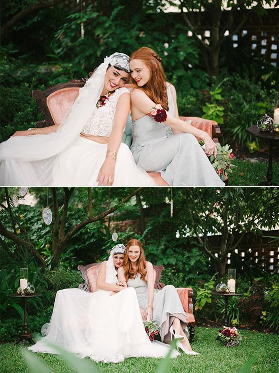 Two women in wedding attire smile in a garden