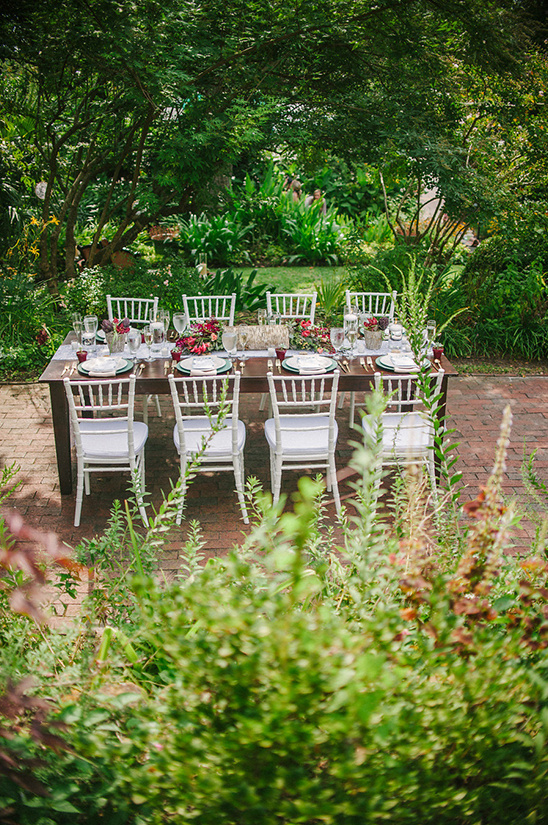 Elegant outdoor dining table setting amidst lush greenery