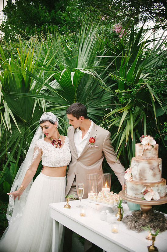 Couple at an outdoor wedding, with cake and greenery around them