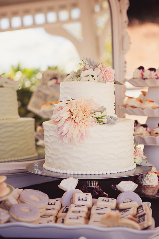 Elegant two-tiered wedding cake with floral decorations and cookies
