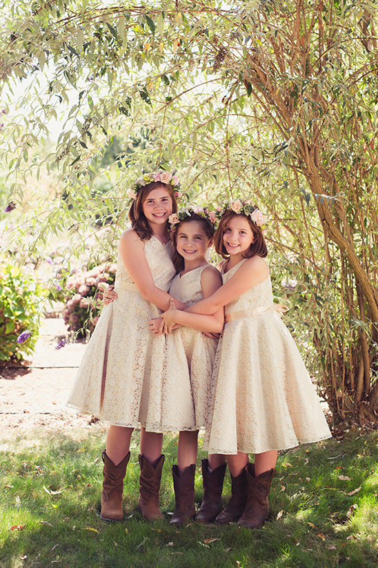 Three flower girls smiling in dresses and cowboy boots